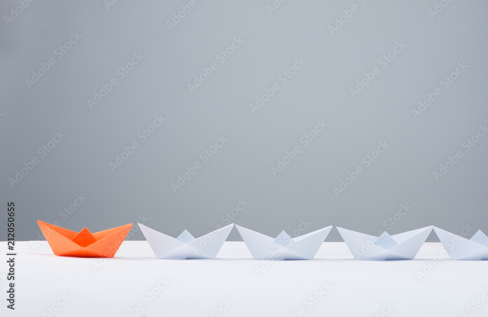 Leadership concept. Red paper ship leading among white Leadership concept. Red paper ship leading among white