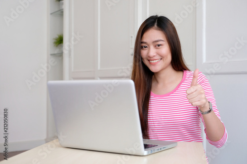 Young asian woman thumb up while working with laptop computer, people working with positive expression © mangpor2004