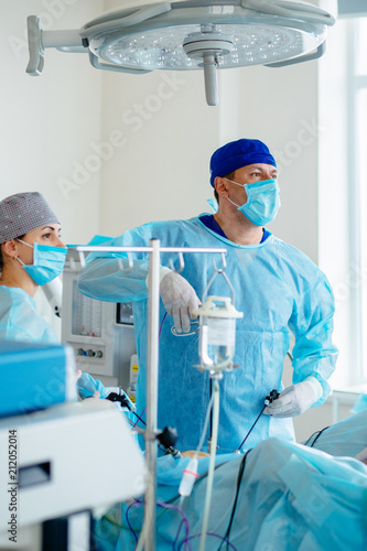 Vertical shot of male surgeon s holing the instrument in abdomen of patient. The surgeon s doing laparoscopic surgery in the operating room. Minimally invasive surgery.