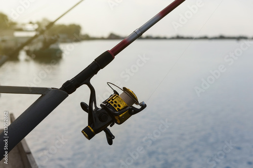 fishing rod with spool spinning stands on the bracket, close-up, fishing on the river, early morning