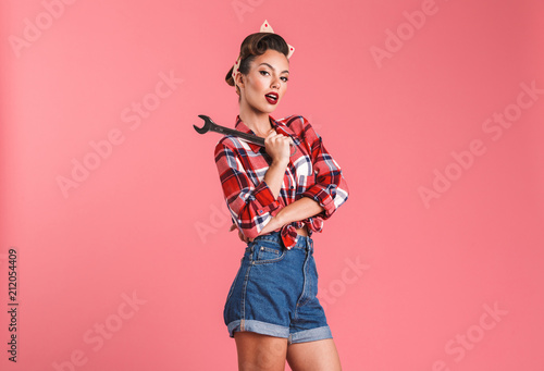 Fotografi Amazing young pin-up woman holding wrench.