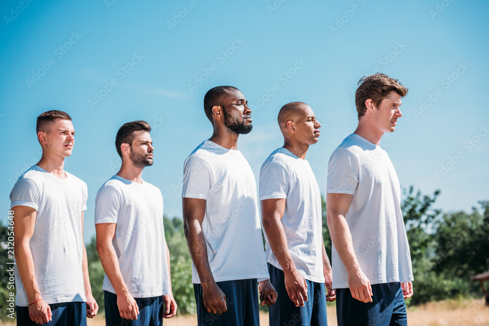 side view of interracial young soldiers standing on range on summer day side view of interracial young soldiers standing on range on summer day