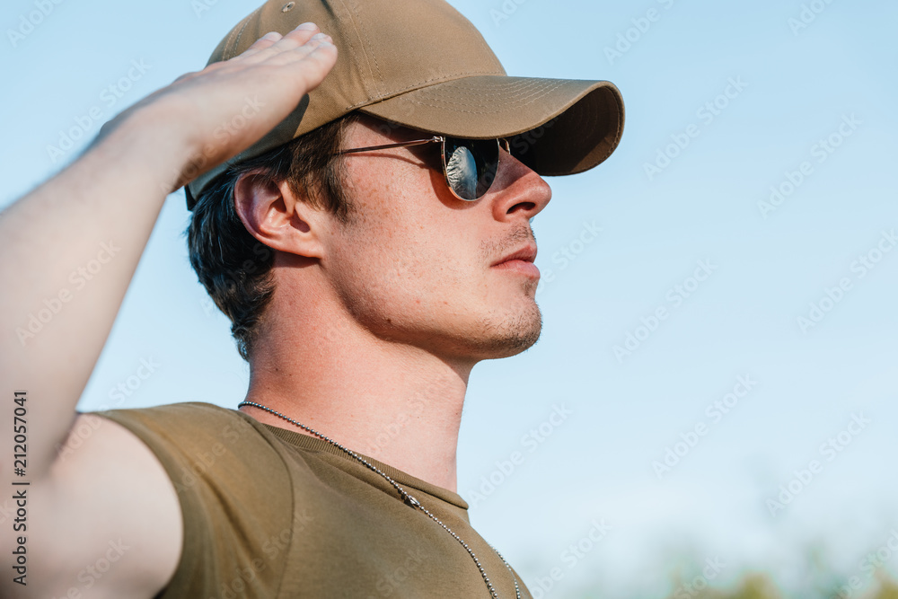 side view of young soldier in cap and sunglasses against blue sky side view of young soldier in cap and sunglasses against blue sky