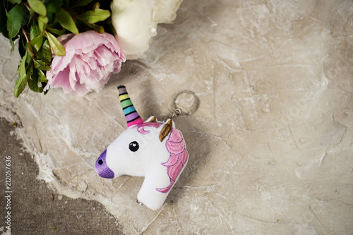 Head of a unicorn key chain top view with peonies photo