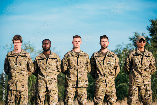 portrait of multiracial confident soldiers in military uniform standing on range