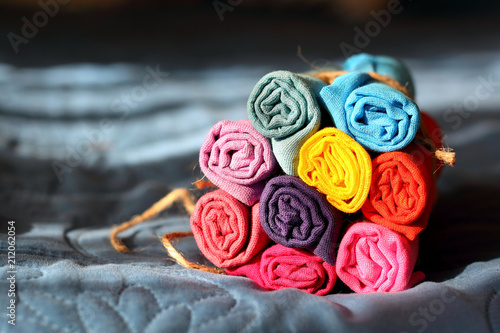 Rolls of multicolored clothes bound by a piece of rope