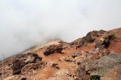 Large volcanic rocks line dirt path on Mt. Asahi in Hokkaido, Japan