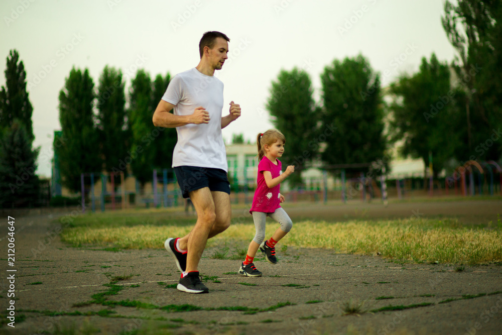 Athletic young father and little daughter running in stadium at sunset. Healthy lifestyle Athletic young father and little daughter running in stadium at sunset. Healthy lifestyle