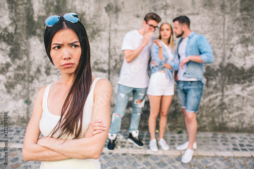 Valokuva Upset young chinese girl is standing in front of picture and looking to theside