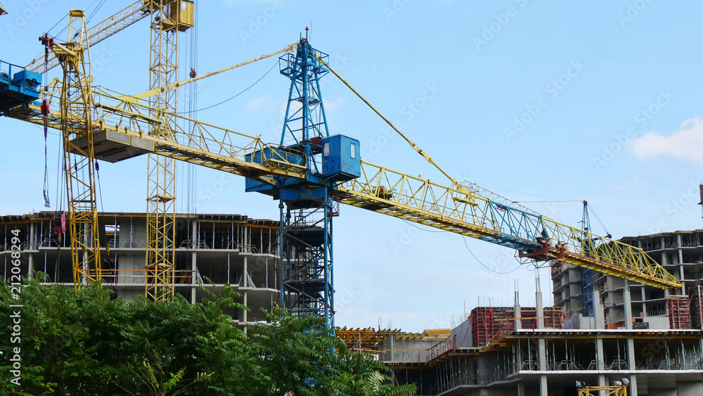 Cranes near buildings. Construction site. Concrete building under construction.
