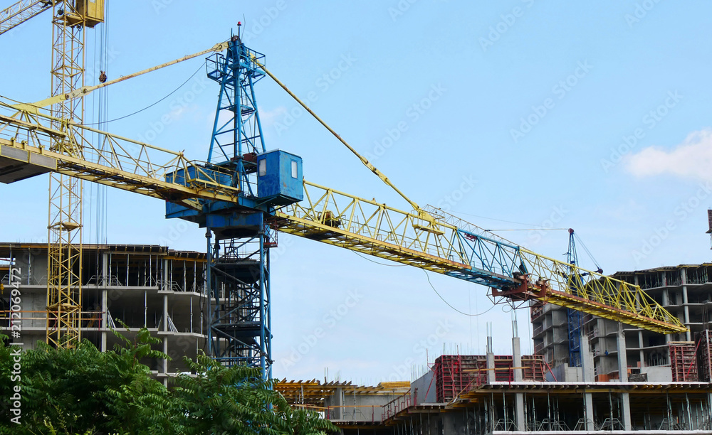Crane near buildings. Construction site. Concrete building under construction.