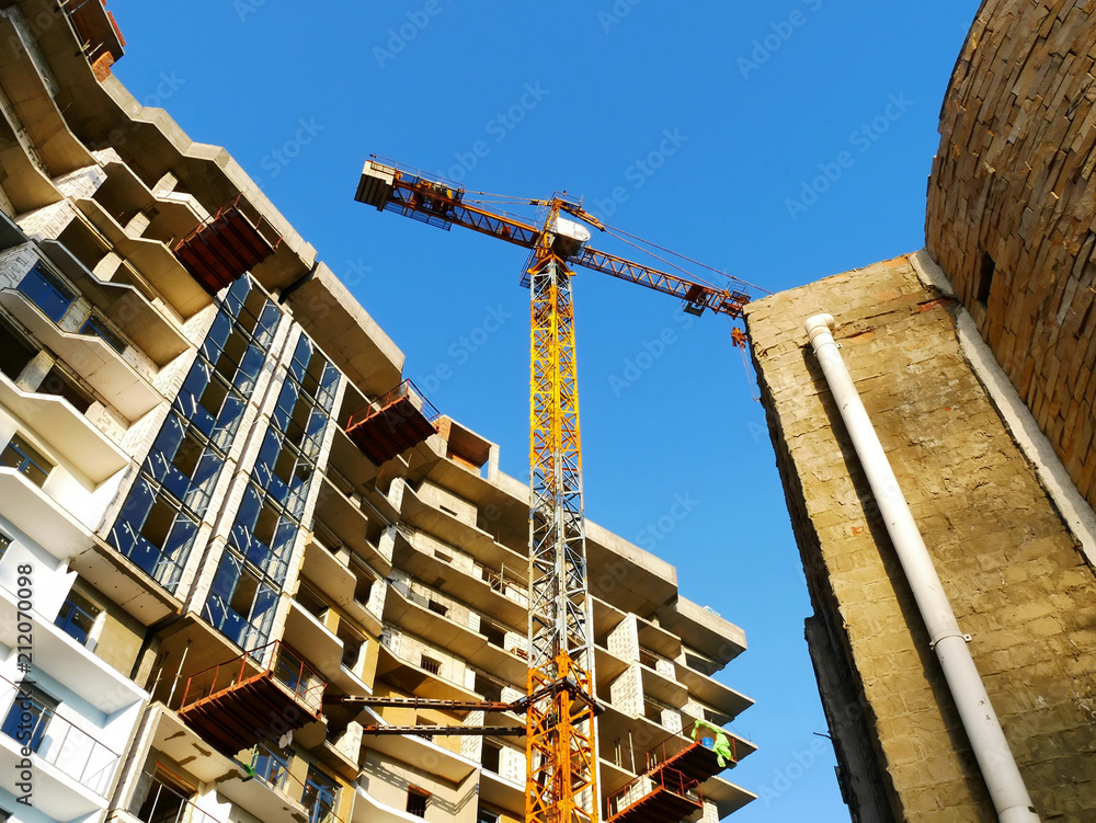 Construction crane against the background of the building under construction