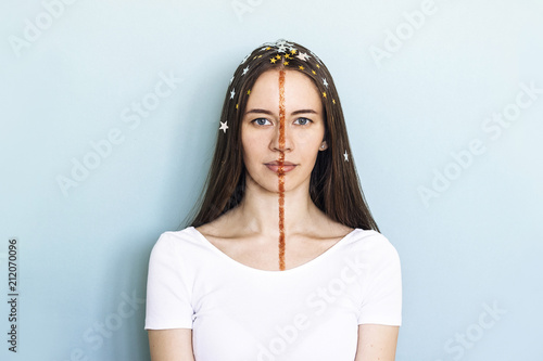 Young woman with fantasy makeup. Model with stars and glitter strip on blue background. Creative concept of beauty, fun.