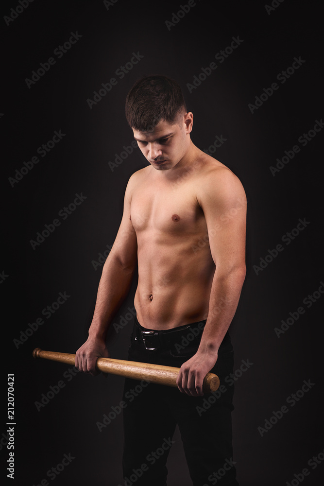 The young gue on a black wall in fighting pose with baseball bat Stock  Photo | Adobe Stock