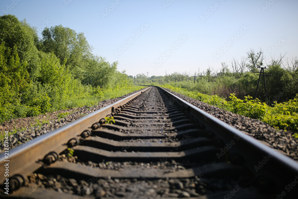 Rail tracks in the green field. Railway transport industry. Empty road on summer day. Travel lifestyle motivation photo.