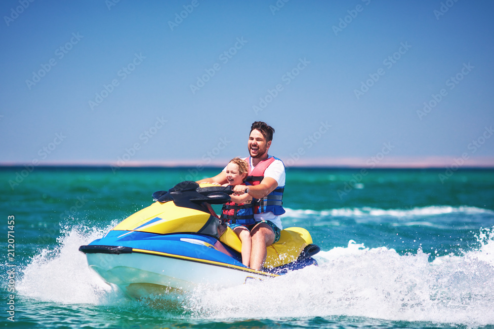 happy, excited family, father and son having fun on jet ski at summer vacation happy, excited family, father and son having fun on jet ski at summer vacation