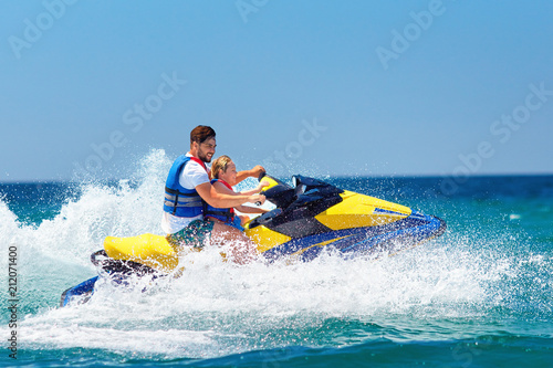 happy, excited family, father and son having fun on jet ski at summer vacation photo