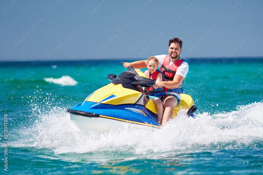 happy, excited family, father and son having fun on jet ski at summer vacation happy, excited family, father and son having fun on jet ski at summer vacation