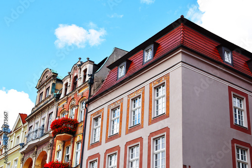 Old town buildings with bright colorful decorative facades on blue sky background in summer morning in poland with copy space for text.