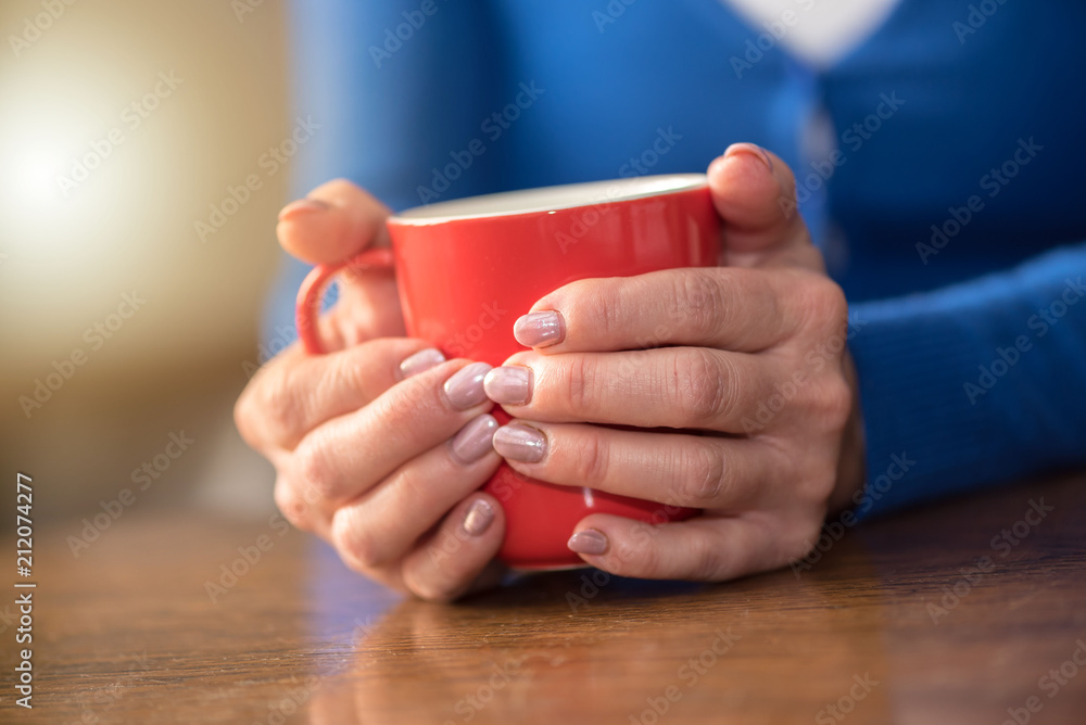 Woman's hands holding a mug of hot beverage Woman's hands holding a mug of hot beverage