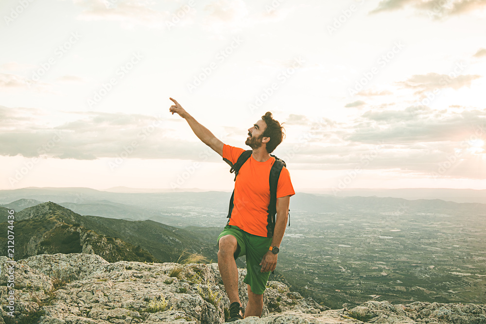 Man on the mountain pointing towards the sky. Guy practicing trekking