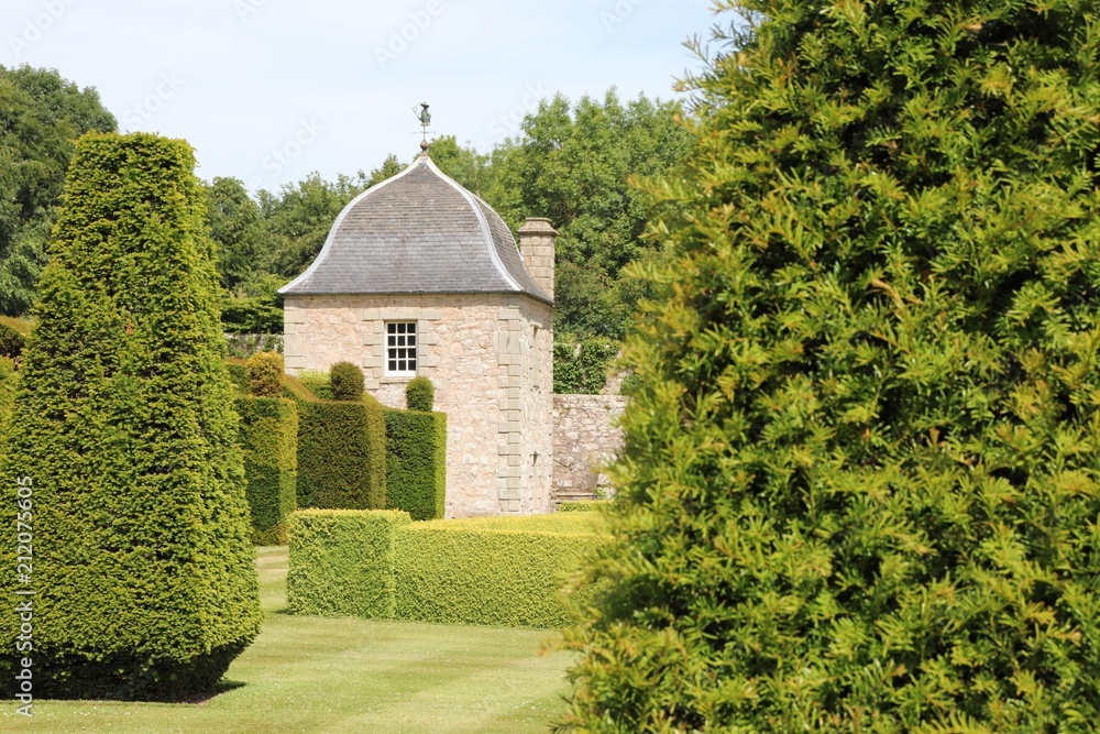 Old tower in between hedges and trees in formal garden