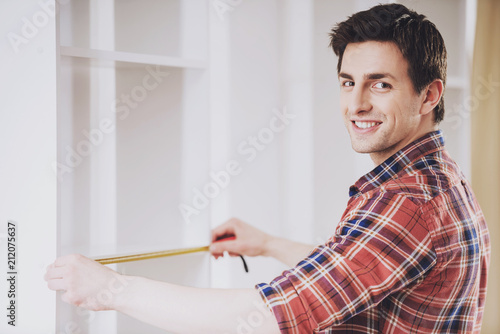 Smiling Man Installing Furniture in New Home.