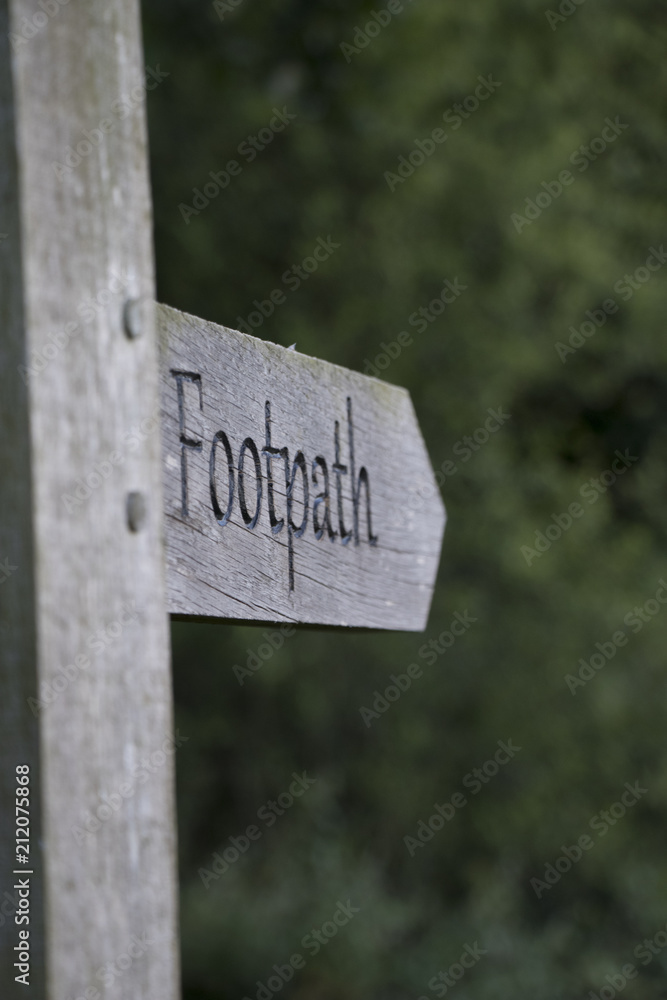 Old wooden footpath sign in a rural forest scene