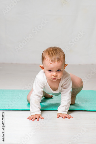 the baby is performing physical exercises on the yoga mat. Baby Yoga