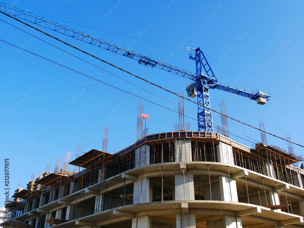 Concrete building and crane against blue sky. Construction site. Concrete building and crane against blue sky. Construction site.
