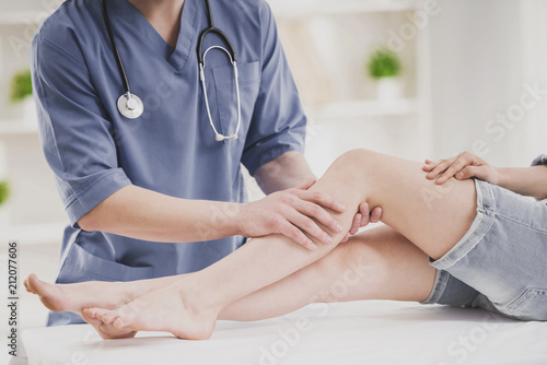 Close up. Doctor Comfforting Leg of Sitting Woman. photo