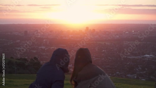 4K Young People having picnic on hill overlooking big city at sunset