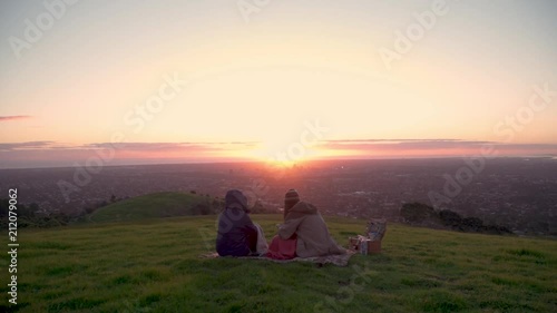 4K Young People having picnic on hill overlooking big city at sunset 1