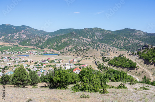 Russia, the Republic of Crimea, Sudak city district, Vesyoloe village. 06/08/2018: View of a settlement in a mountain valley: houses, outbuildings, vineyards