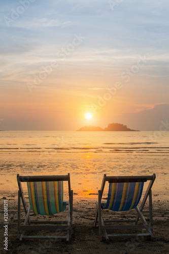 Couple of sun loungers on the beach during sunset.