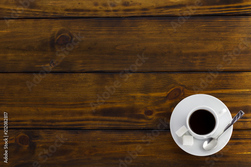 Black coffee with 2 sugars, white cup on a brown wooden table. Top view