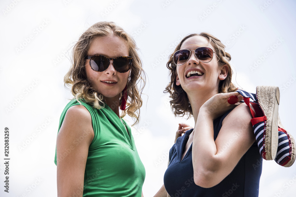 Two lovely models are posing on wooden pier at riverside.Outdoor fashion conception. Two lovely models are posing on wooden pier at riverside.Outdoor fashion conception.
