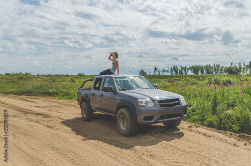 girl on an SUV in a field on a sandy road