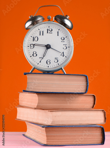 Alarm clock on top of piles of books
