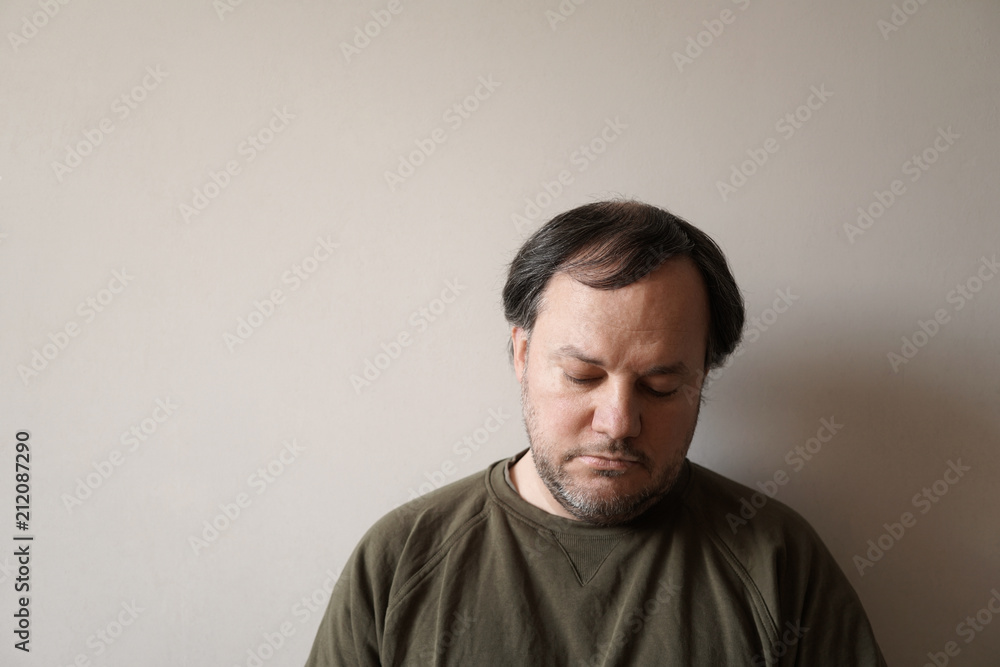 depressed man in his forties leaning against wall with copy space. depression or midlife crisis concept. depressed man in his forties leaning against wall with copy space. depression or midlife crisis concept.