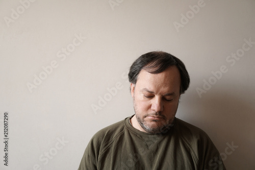 depressed man in his forties leaning against wall with copy space. depression or midlife crisis concept. photo