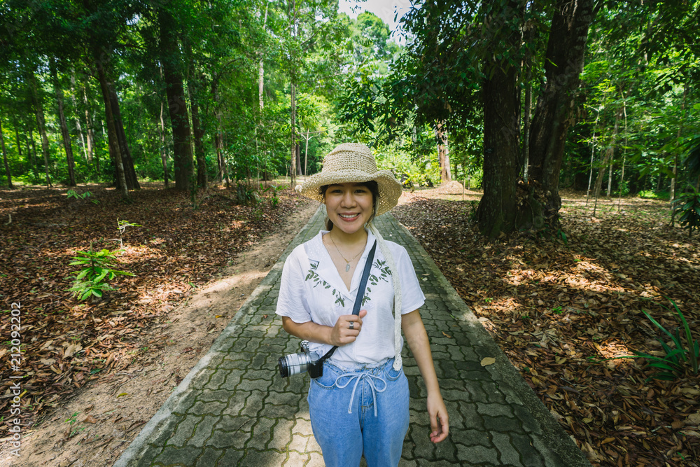 Asian woman walking on brick walkway in the forest.