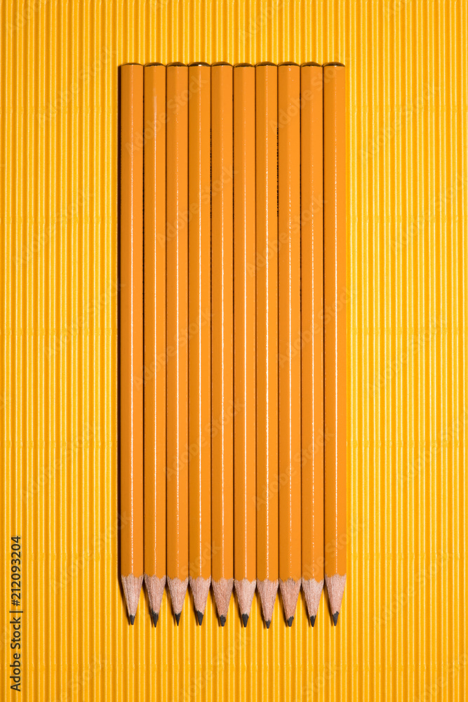 top view of arranged graphite pencils placed in row on yellow top view of arranged graphite pencils placed in row on yellow