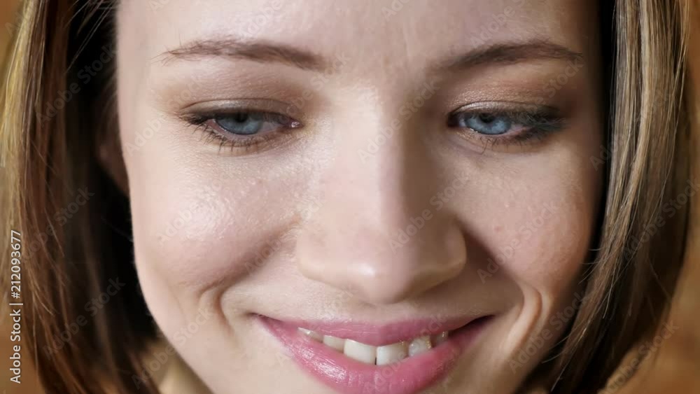 Face of young attractive shy girl is smiling, watching at camera, brick background Face of young attractive shy girl is smiling, watching at camera, brick background