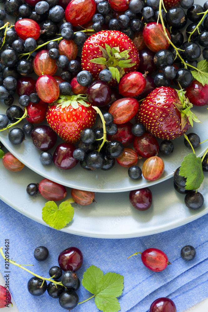 Fruit salad with strawberry, blueberry, cherry, gooseberry and black currant on wooden gray background. Flat lay. Top view Fruit salad with strawberry, blueberry, cherry, gooseberry and black currant on wooden gray background. Flat lay. Top view