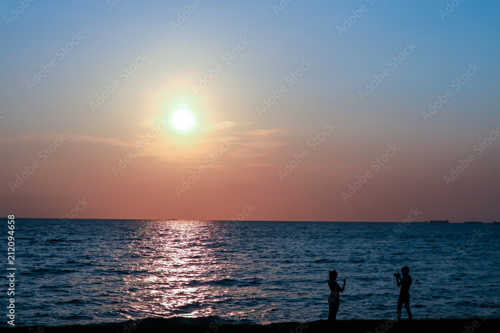 silhouette two people standing take photo on beach sunset