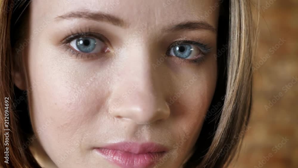 Face of young worried girl is watching at camera, blurred background Face of young worried girl is watching at camera, blurred background