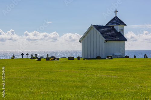 A white small burial chapel and the scenic cemetery on the coast of the ocean in the Varhaug, region Jaeren in Norway