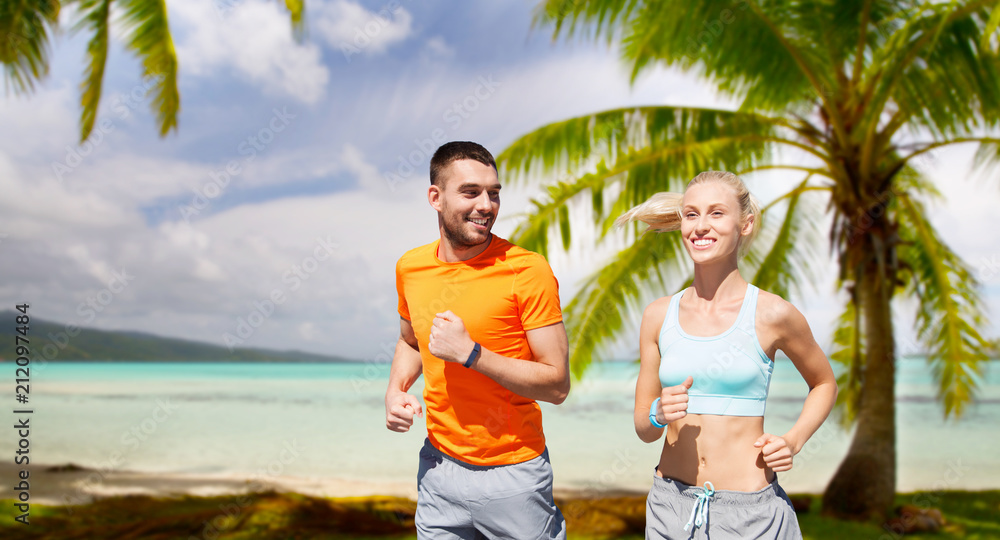 fitness, sport and healthy lifestyle concept - smiling couple with heart-rate watch running over tropical beach background in french polynesia