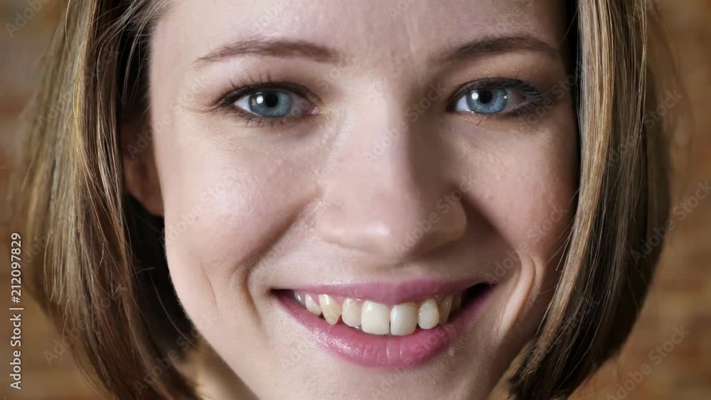 Face of young happy girl is smiling, watching at camera, flirt concept, brick background Face of young happy girl is smiling, watching at camera, flirt concept, brick background
